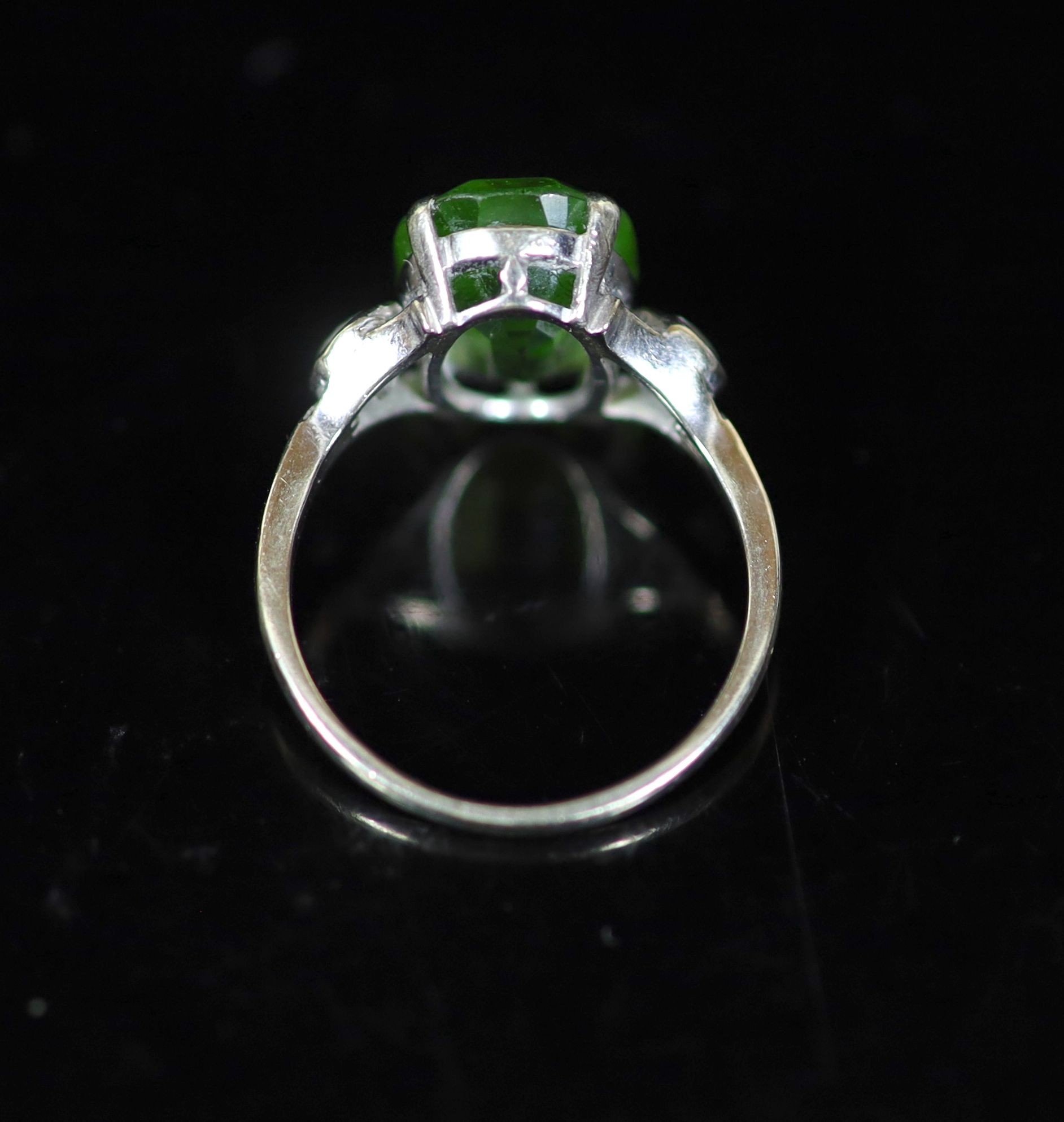 A 9ct white gold oval cut peridot set dress ring, with diamond set shoulders